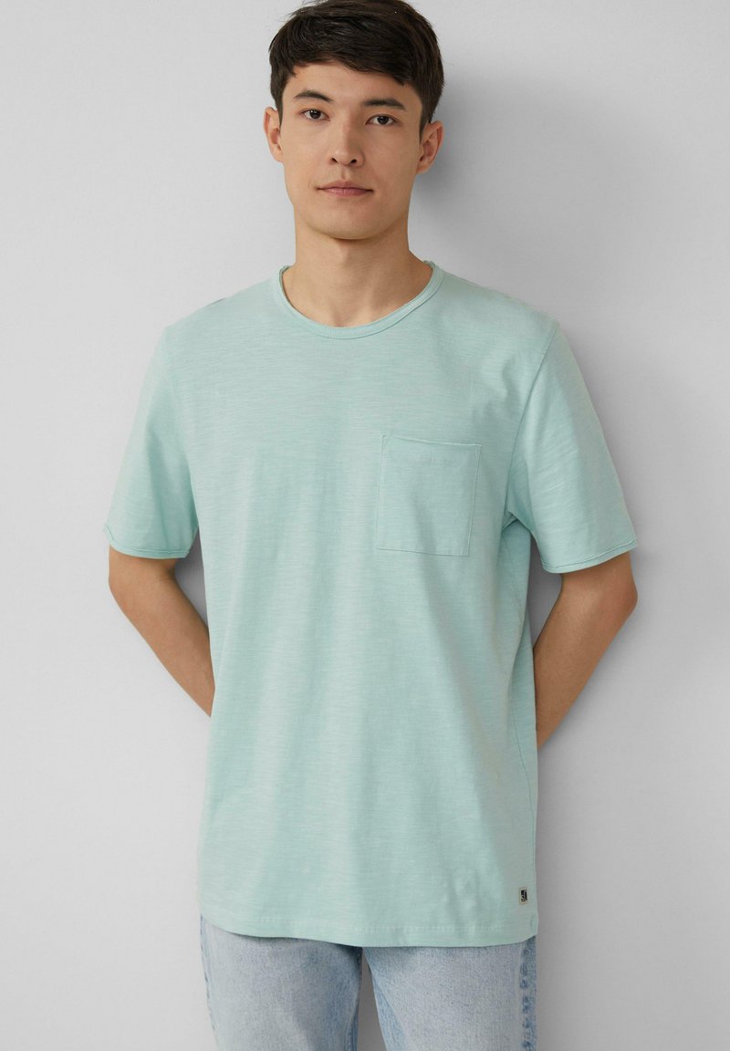 Licht mintgroene t-shirt gemaakt van een zachte stof, met een ronde hals en een enkele borstzak. Het ontwerp heeft korte mouwen en een relaxte pasvorm.