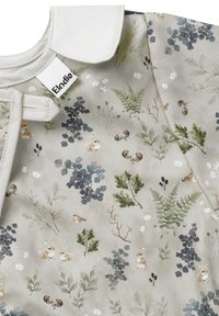 Blommönstrad tyg med kaniner, blad och ormbunkar i dämpade färger. Kragen är vit, med ett knytband vid halslinningen.