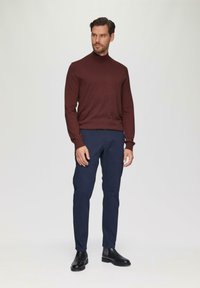 Bordeaux turtleneck sweater, slim-fit marineblauwe broek en zwarte enkelboots. Soepele textuur met een aansluitend ontwerp, minimalistische stijl.