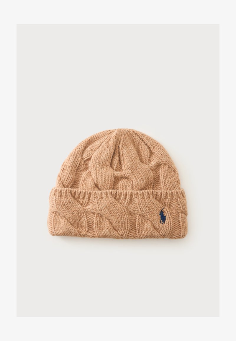 Bonnet en laine beige tricoté avec motif torsadé et petit logo bleu brodé sur le revers, présenté sur fond clair.