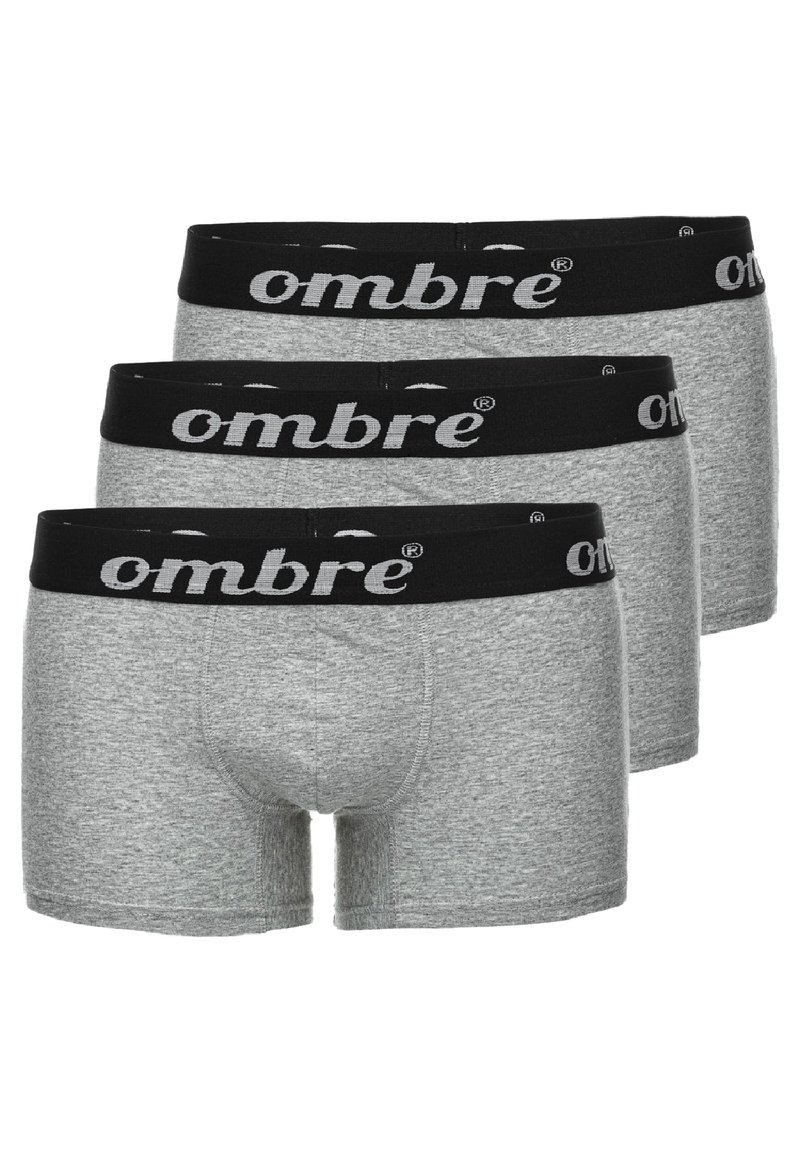Calzoncillos de algodón gris con una cinturilla elástica negra que presenta el logo "ombre" en blanco. Tres pares exhibidos, con textura suave.