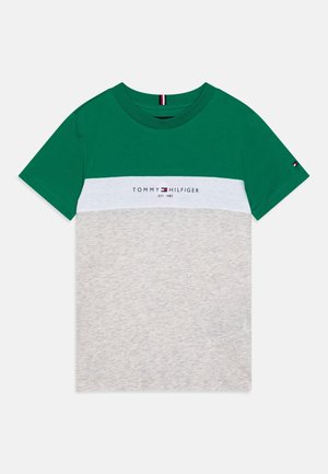 T-shirt à manches courtes à blocs de couleurs avec le haut vert, une bande blanche au milieu avec le logo "Tommy Hilfiger", et le bas gris clair.
