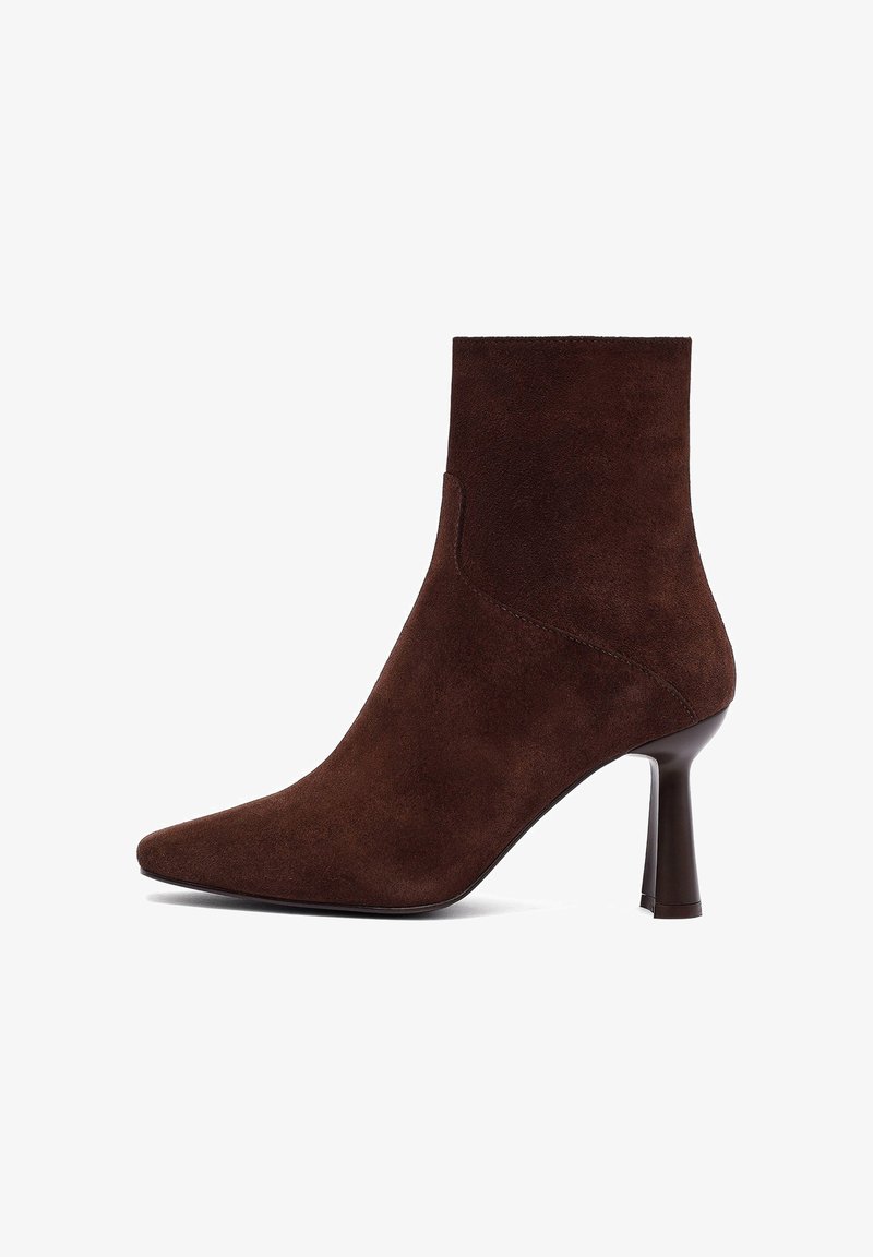 Bottine en daim marron avec un bout pointu, un design ajusté et un talon haut fin, présentant des lignes épurées et une texture lisse.