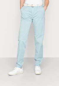 Pantalon chino bleu ciel en coton, avec poches latérales, ceinture tressée et coupe décontractée, assorti à des baskets blanches.