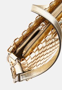 Złota torebka pleciona z teksturowanym wykończeniem, z zamknięciem na zamek, podwójnymi przegrodami oraz metalowymi detalami. W zestawie regulowany pasek.