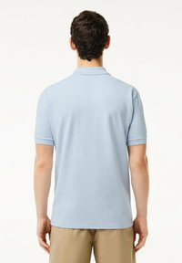 Ljusblå kortärmad polo med en mjuk textur, en klassisk krage och subtila ribbade detaljer på ärmar och fåll.