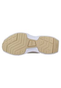 Semelle de chaussure avec une surface en caoutchouc beige, présentant un motif de traction texturé et des accents blancs, des bords incurvés et un détail de logo central.