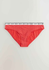 Perizoma in cotone rosso con pois bianchi, dotato di una vita elastica con logo "NEXT" in bianco e nero. Progettato con un taglio a vita bassa.