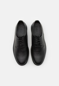 Black leather shoes with a smooth texture, rounded toe, lace-up design, and minimal stitching. Brand name "ZIGN" embossed on the insole.