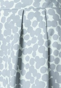 Vaaleansininen hame, jossa on teksturoidusta kankaasta valmistettu valkoinen abstrakti pilkku kuvio; sisältää laskostetun muotoilun volyymin lisäämiseksi.