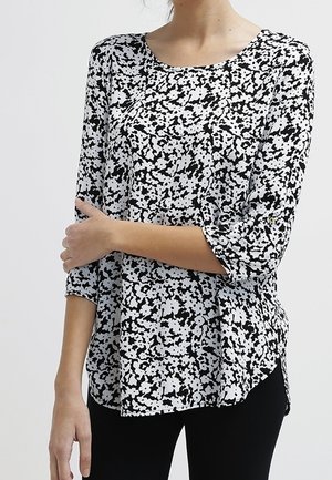 Schwarz-weißer Shirt mit rundem Halsausschnitt, dreiviertelärmeln und einem strukturierten, abstrakten Druck. Lockere Passform mit seitlichen Schlitzen.