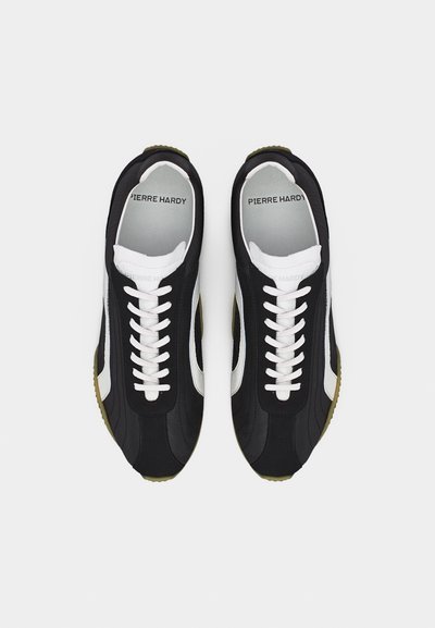 Μαύρα και λευκά χαμηλά αθλητικά παπούτσια με λευκά κορδόνια, σόλα ελιάς και την επιγραφή "Pierre Hardy" στο εσωτερικό της φτέρνας.