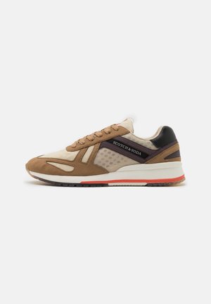 Tan and beige sneaker with mesh and suede materials, featuring a black accent, textured panels, and a white sole with red detail.