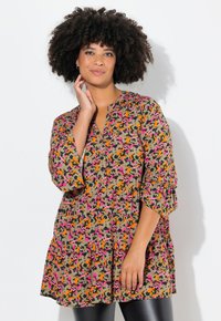 Multikleurige tuniek met een losse pasvorm, featuring een V-hals, driekwart mouwen en een uitlopende zoom. Patroondesigns zijn oranje, roze en groen.