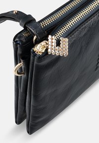 Portefeuille en cuir noir avec deux compartiments zippés, ferrures dorées, surface texturée et un élément d'accent distinctif sur la tirette du zip.