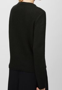 Svart stickad tröja med en texturerad mönster, rundad halsringning och långa ärmar, med en något lös passform och ribbad fåll.