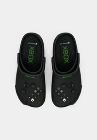 Zwarte klompen met een gestructureerd oppervlak, voorzien van geïntegreerde Xbox-controllerknoppen en een groen logo op de band. Lichtgewicht ontwerp.