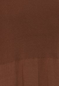 Bruine gebreide stof met twee texturen: een ribbelige bovenkant en een gladde onderkant, wat een gelaagd effect creëert.