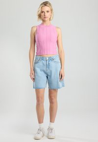 Vaaleanpunainen ribbikroppitoppi, jossa on korkea kaula-aukko; yhdistettynä vaaleansinisiin farkkushortseihin, joissa on räjähtävän reunan yksityiskohtia. Yhdistettynä valkoisiin tennareihin ja sukkiin.