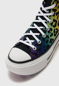 High-top sneaker featuring a multicolor leopard print design on canvas, black accents, white laces, and a rubber toe cap with purple detailing.