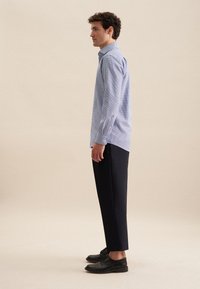 Camicia button-up a quadri blu chiaro con colletto, abbinata a pantaloni navy scuri e scarpe nere. La camicia presenta maniche lunghe e polsini con bottoni.