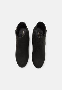 Bottines en daim noir avec une finition lisse, fermeture éclair sur le côté et bout arrondi. Design simple sans motifs ou accents visibles.