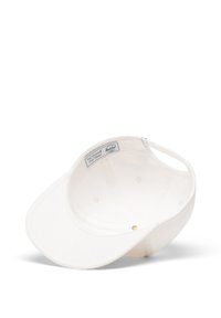 Gorra de béisbol de algodón blanca con visera curva, etiqueta interior y un acento dorado en el cierre. Textura suave, diseño no estructurado.