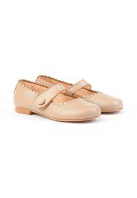 Zapatos de cuero beige con borde festoneado, puntera redondeada y cierre de correa con un botón redondo. Diseño de suela plana con textura ligera.