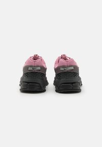 čierne a ružové tenisky Nike s textúrovaným sieťovaným zvrškom, ktorý má mriežkový vzor na päte, pútka a hrubú gumovú podrážku.