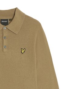 Beige pikétröja av mjukt tyg, med krage, tre knappar och en liten gul och svart örnlogotyp på vänster bröst.