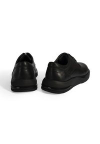 Zwarte leren schoenen met een gladde textuur, ronde neus, lage hak en dikke rubberen zolen. Kenmerken zijn minimale stiksels en een sleek ontwerp.
