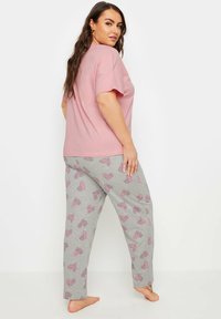 Ljusrosa löst sittande t-shirt parat med grå pyjamasbyxor som har mönster av rosa hjärtan och ränder. Mjuk tyg med avslappnad design.