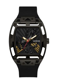 Montre-bracelet noire avec boîtier rectangulaire à cadre ouvert, aiguilles dorées et rouges, figure de cheval noir en relief, et logo "GUESS" sur le cadran.