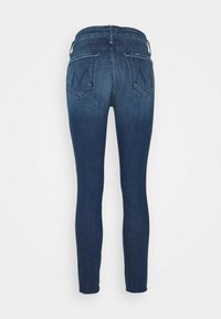 Jeans ajustados en denim azul oscuro con una textura suave, con dos bolsillos traseros y un detalle de costura en contraste. Sin hardware visible.
