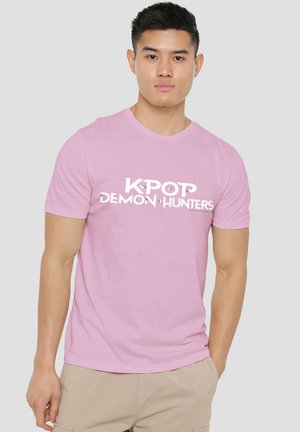 Rosa Baumwoll-T-Shirt mit einem weißen Grafikdruck, der den Text "K-POP DEMON HUNTERS" zeigt. Klassischer Rundhalsausschnitt und kurze Ärmel.