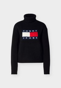 Pull noir avec manches côtelées et col roulé. Comprend un patch logo à l'avant en bleu, rouge et blanc avec le texte « TOMMY JEANS ».