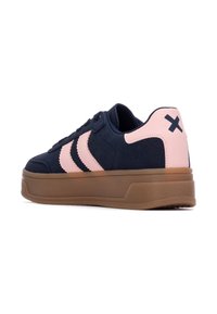 Sneaker blu navy con accenti rosa chiaro, caratterizzato da tre strisce e una suola spessa in gomma marrone, realizzato in suede e materiali traspiranti.