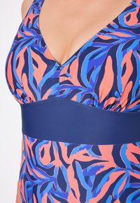 Multikleurige badpak met een blauw en koraalkleurig bladerenpatroon. Het heeft een diepe V-halslijn, geacrêteerde stof en een effen blauwe band onder de buste.