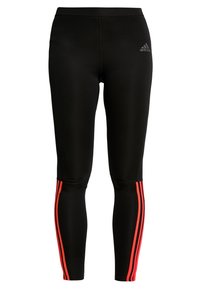Leggings de sport noirs avec des bandes latérales rouges, fabriqués à partir d'un matériau extensible. Dotés d'un design ajusté et d'un petit logo noir à la taille.