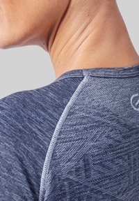 Marineblauw sportshirt met een gestructureerde stof en een gemêleerd patroon. Bevat contrasterende stiksels langs de halslijn en de schoudernaden.