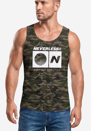 Mann trägt Camouflage-Top mit "NEVERLESS ON Everyday Athletics" Schriftzug und Grafiken, kombiniert mit blauen Jeans, vor einfachem Hintergrund.
