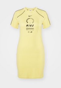 Żółta sukienka krótki rękaw z bawełny. Posiada okrągły dekolt, logo Nike oraz nadruk z przodu, a także kontrastowe szwy na rękawach.