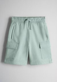 Shorts vert clair longueur genou avec taille élastique, cordon de serrage, poches latérales zippées et grandes poches cargo à rabat sur chaque jambe.