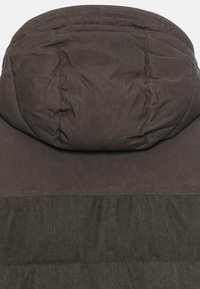 Puffjakke i mørkegrå, med et blødt, tekstureret stof, hætte og ribbet nederste sektion. Minimalistisk design med synlige sømme.