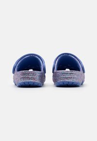 Modré dřeváky s třpytivým fialovým a růžovým akcentem na patě. Ohebný materiál, otevřený design zezadu a strukturované podrážky pro lepší přilnavost.