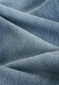 Denim w jasnoniebieskim kolorze, z drobnym splotem diagonalnym i subtelnymi różnicami w kolorze i odcieniu, o gładkim układzie.