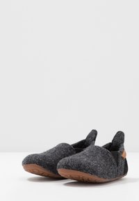 Grijze gevoerde slippers met een ronde neus, elastische zijkanten en een bruine rubberen zool met grippatronen voor extra grip.