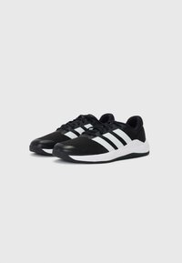 Black athletic shoes with mesh upper, white three-stripe design, padded collar, and rubber outsole for grip. Features a rounded toe.