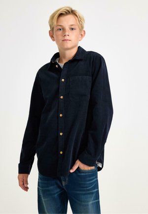 Marineblauwe corduroy overhemd met knopen en een borstzak, met houten knopen en lange mouwen, gecombineerd met denim jeans. Eenvoudig en klassiek design.