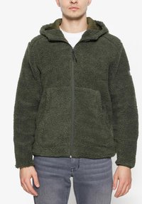 Giacca in pile verde con chiusura a zip e cappuccio, caratterizzata da una superficie testurizzata e tasche frontali. Fodera in tessuto liscio nel colletto.